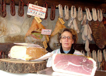 The proprietor at the Charcuterie in St. Girons. Salt-cured country hams, sausages hanging on the wall... and note the big wheel of cheese sitting on a block of wood!